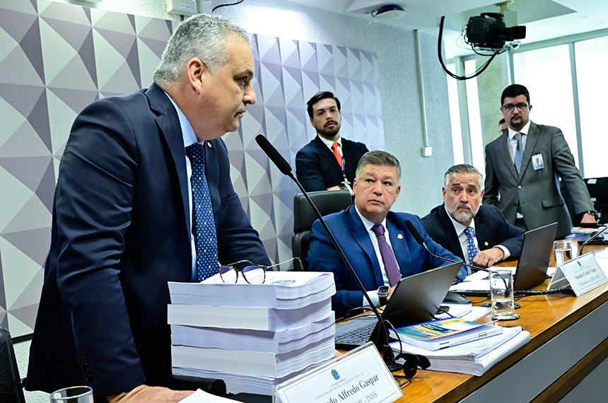 O deputado Alfredo Gaspar apresenta seu relatório, observado pelo senador Carlos Viana, presidente da CMPI, e pelo deputado Paulo Pimenta Fonte: Agência Senado