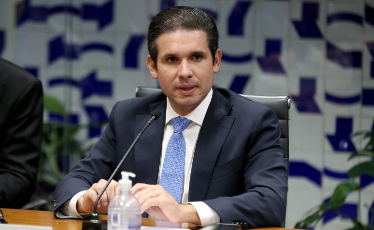 Fotografia oficial do presidente da Câmara dos Deputados, Hugo Motta, vestindo terno escuro e gravata, em ambiente institucional no Congresso Nacional.