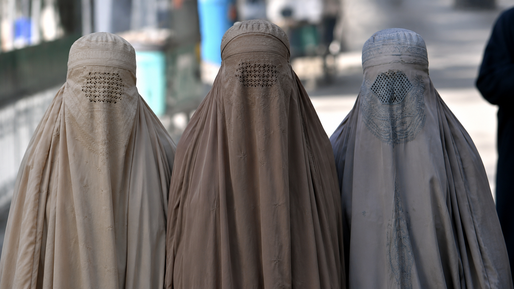 Três mulheres usando burca tradicional, cobrindo totalmente o rosto e deixando apenas a grade nos olhos. Imagem ilustrativa sobre o debate de trajes tradicionais em fotos de documentos oficiais. (gerada por IA)