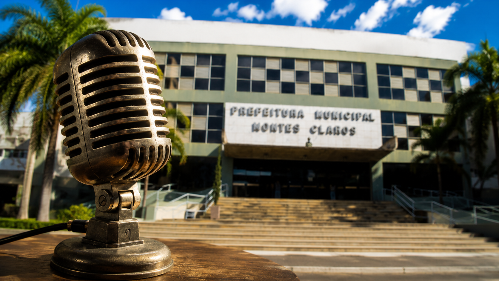 Microfone de estúdio de rádio vintage em destaque com prédio público em plano de fundo desfocado, ilustrando a coluna de Benedito Said sobre populismo e gestão técnica.