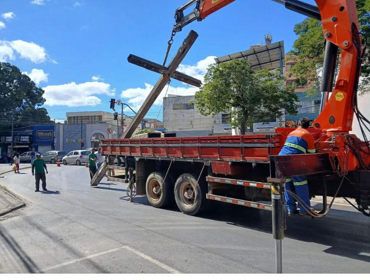 Caminhão com guindaste removendo a histórica Santa Cruz de madeira ao lado da Igreja de Nossa Senhora do Rosário em Montes Claros.